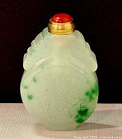 View of the jade perfume/snuff bottle showing detailed carvings and green jade inclusions, standing upright.