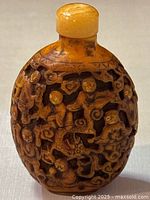 Front view of the snuff bottle displaying carved figures and dragons.