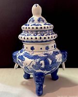 Front view of porcelain incense burner showing detailed blue dragon painting, pierced lid, and ring handles on legs.