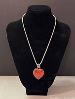 Front view of the necklace on black display showing the coral heart pendant.