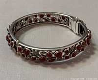 Vintage 925 sterling silver bracelet with multiple red coraline stones arranged in floral and heart-shaped patterns, showing front and side views.