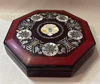 Top view of the closed octagonal box showing the detailed mother of pearl floral and geometric inlay on the lacquered lid.
