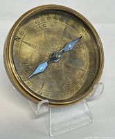 Front view of the vintage brass compass showing compass rose and needle.