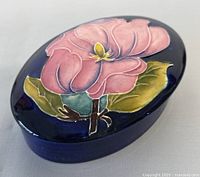 Oval trinket box closed top view showing pink flower design on lid with blue background