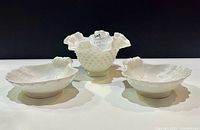 Front view of the three bowls, showing the Fenton milk glass bowl in the center with hobnail texture and ruffled rim, flanked by two leaf-shaped Italian porcelain bowls.