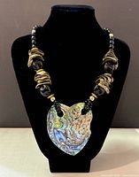 Front view of vintage handmade abalone necklace with heart-shaped pendant displayed on black mannequin bust.