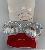 Two clear Baccarat crystal candleholders with original box and card shown from the front.