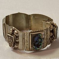 Side view of vintage sterling silver bracelet showing abalone shell inlay and tribal mask design with decorative silver beadwork and engraving.