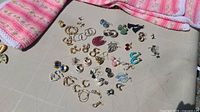 Overhead view of all earrings arranged on a flat surface, showing a diverse mix of metal colors, styles, and closures.