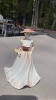 Front and side view of the Victorian lady porcelain figurine on an outdoor surface, showing detailed multicolor painting and dress design.