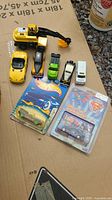 Collection of various die-cast toy cars including construction vehicles, sports cars, police van, and collectible Hot Wheels cars