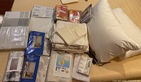 Top view of bedding and curtain items laid out on bed, including white pillow, pillowcases, and folded curtains along with Select Edition shower curtains in blue packaging.