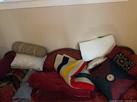 View of multiple pillows and blankets on a sofa including the Hudson Bay striped fleece blanket and pillows in various colors and designs.