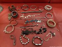 Overview of 18 assorted bracelets on red background showing metal, bead, chain, and mesh styles.