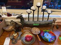 Overview of lot items including the ram-shaped metal candle holder with five candles, brass hand-shaped decorations, colorful glass clock, and other accessories.