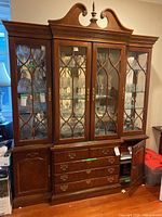 Front view of full American Drew wood china cabinet with glass paneled doors, carved details at top, four drawers with metal pulls, and two cabinet sections at bottom.