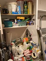 Wide view of shelves holding Raid spray, various cleaning bottles, containers, and mug