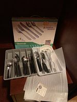 Full view of the 40-piece Savannah stainless steel flatware set organized in the hardwood flatware insert along with the included accessories and placemats beneath.