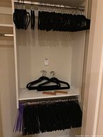 Shelves and hanging rods with large quantities of black velvet-covered hangers and wooden clip hangers displayed.