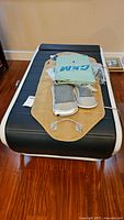 Front view of Ceragem massager bed with beige mat, gray foot modules, green covers