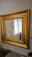 Full view of square mirror with gold antiqued frame showing reflection in glass.