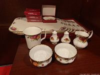 Photo of the various Royal Albert Old Country Roses items including sugar bowls, creamer, mug, salt and pepper shakers, and placemats.