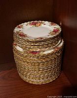Stack of Royal Albert Old Country Roses china plates with gold scalloped edges and floral rose pattern.