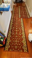 Long view of both runners placed on hardwood floor showing floral pattern and borders.