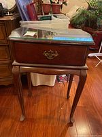 Full view of wood side table with flat top, brass hardware, and cabriole legs on hardwood floor