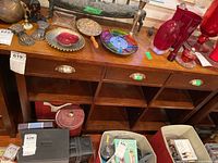 Front view of the wooden sideboard showing the top surface with decorative items and the drawer pulls on the front, along with the six cubby compartments beneath.