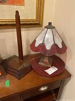 Full view showing lamp on wooden surface next to another item.