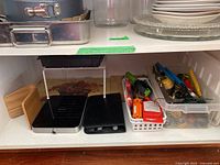 Overview of the shelf with black metal cookbook holder next to hand tools organized in white plastic baskets.