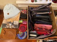 Top view of assorted ladies wallets, small change purses, light blue knit winter hat, and a shirt in original packaging with owl graphic.