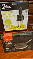 Photo showing boxed Shine Kitchen Co. Cold Press Vertical Slow Juicer and Emura frying pan box stacked together