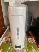 White portable kettle in plastic wrap with digital display and touch controls