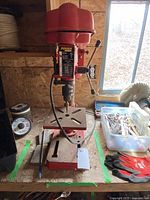 Photo showing full Power Max drill press on a bench with drill bits on the right and gloves visible.