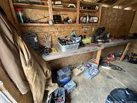 Wide view of shed bench with coveralls, tool bag, compressor and hand tools