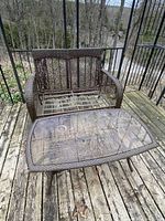 Photo showing brown faux wicker settee frame and matching coffee table with glass top on wooden deck outdoors.