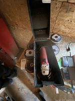 Skilsaw power tool inside black plastic case with lid open, surrounded by various circular cutting blades and discs.