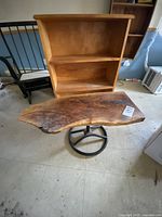 Front view showing wooden bookcase and rough cut wood table with live edge and metal base.