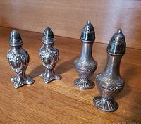 Both pairs of antique Viking silverplate salt and pepper shakers side by side on wooden surface