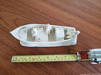 Top-down view of the white handcarved fishing boat with measuring tape showing length approximately 75cm.