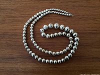 Necklace coiled to show bead sizes and finish on wood tabletop