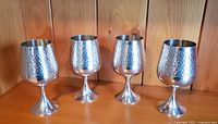 Four pewter wine glasses displayed together, showing hammered texture surface and shape.