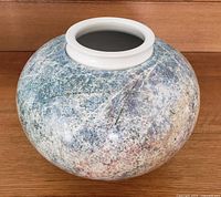 Full view of large round pottery vase showing textured speckled glaze in blue, green, and earth tones with off-white lip.