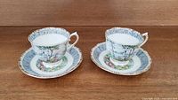 Two Royal Albert Silver Birch teacups with matching saucers, front view, placed on wooden surface.