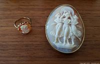 Front view of cameo ring and oval brooch side by side on wood surface