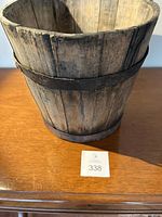 Front and top view of rustic antique wooden sap bucket on a wooden surface with a lot number card visible.