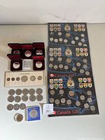 Overview of entire lot: five presentation cases, Canada year set, three Canada 125 folders, loose Canadian dollars and U.S. half dollars, two commemorative packages