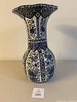 Full view of tall Delft blue trumpet vase with floral decorations on white ceramic.